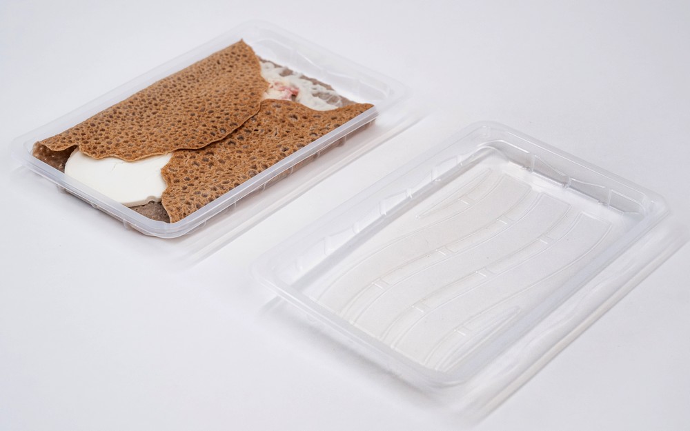 Barquette en plastique transparente contenant une galette bretonne fraîche, présentée dans un emballage moderne et hygiénique qui met en valeur l’authenticité de cette spécialité culinaire.