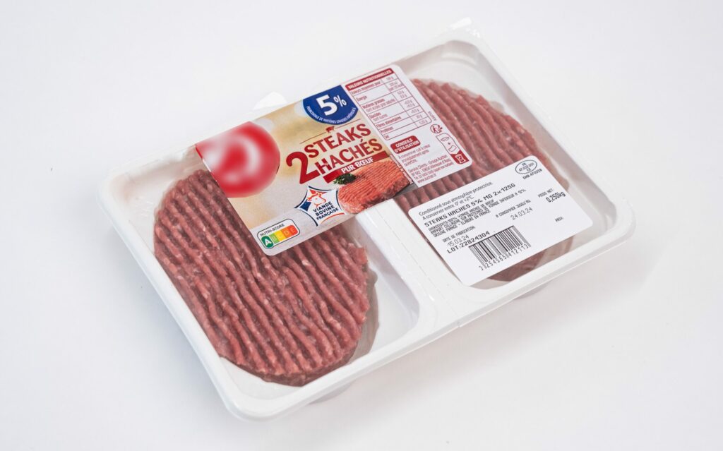 Barquette en plastique sécable operculé contenant des steaks hachés, conçue pour préserver la fraîcheur et la qualité du produit tout en offrant un conditionnement moderne et hygiénique.