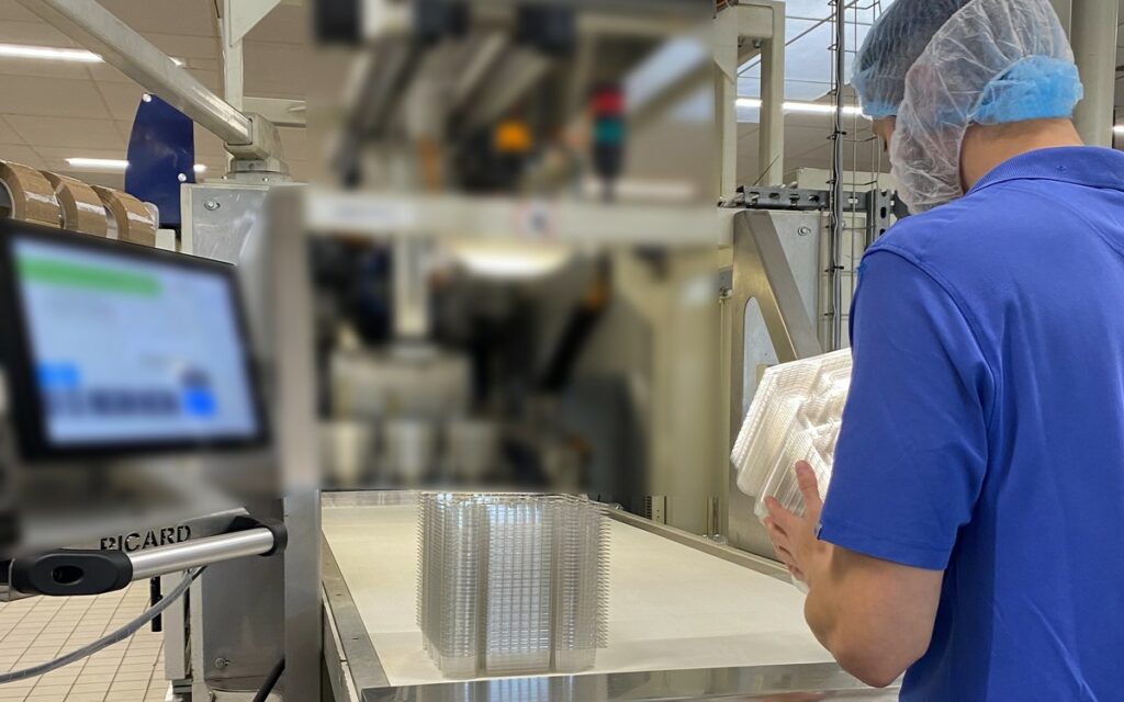 Opérateur de thermoformage inspectant minutieusement les barquettes en fin de ligne de production, s'assurant de leur conformité aux standards de qualité et de sécurité.