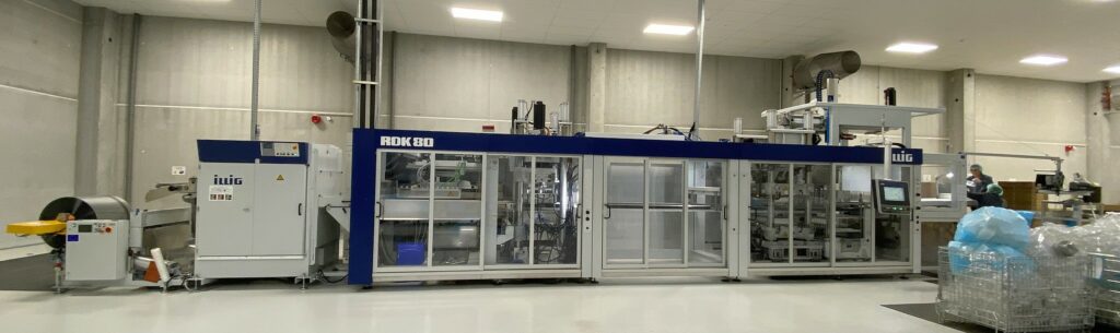 La machine thermoformage RDK80 en fonctionnement dans un environnement industriel moderne, illustrée avec son système de contrôle automatisé et sa capacité à produire des emballages plastiques de haute qualité.