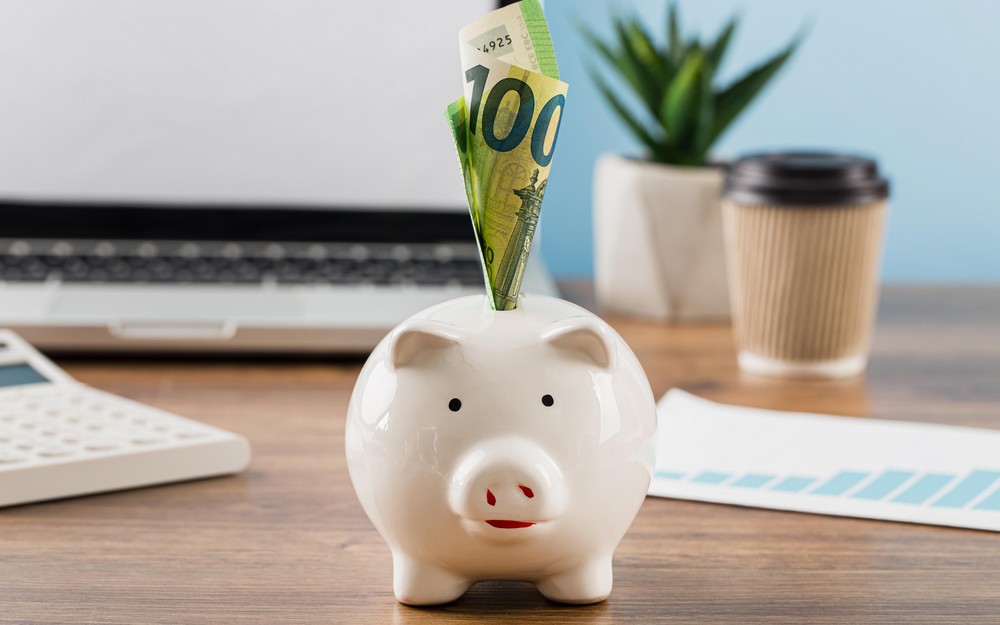Tirelire cochon avec un billet de 100 euros sur un bureau